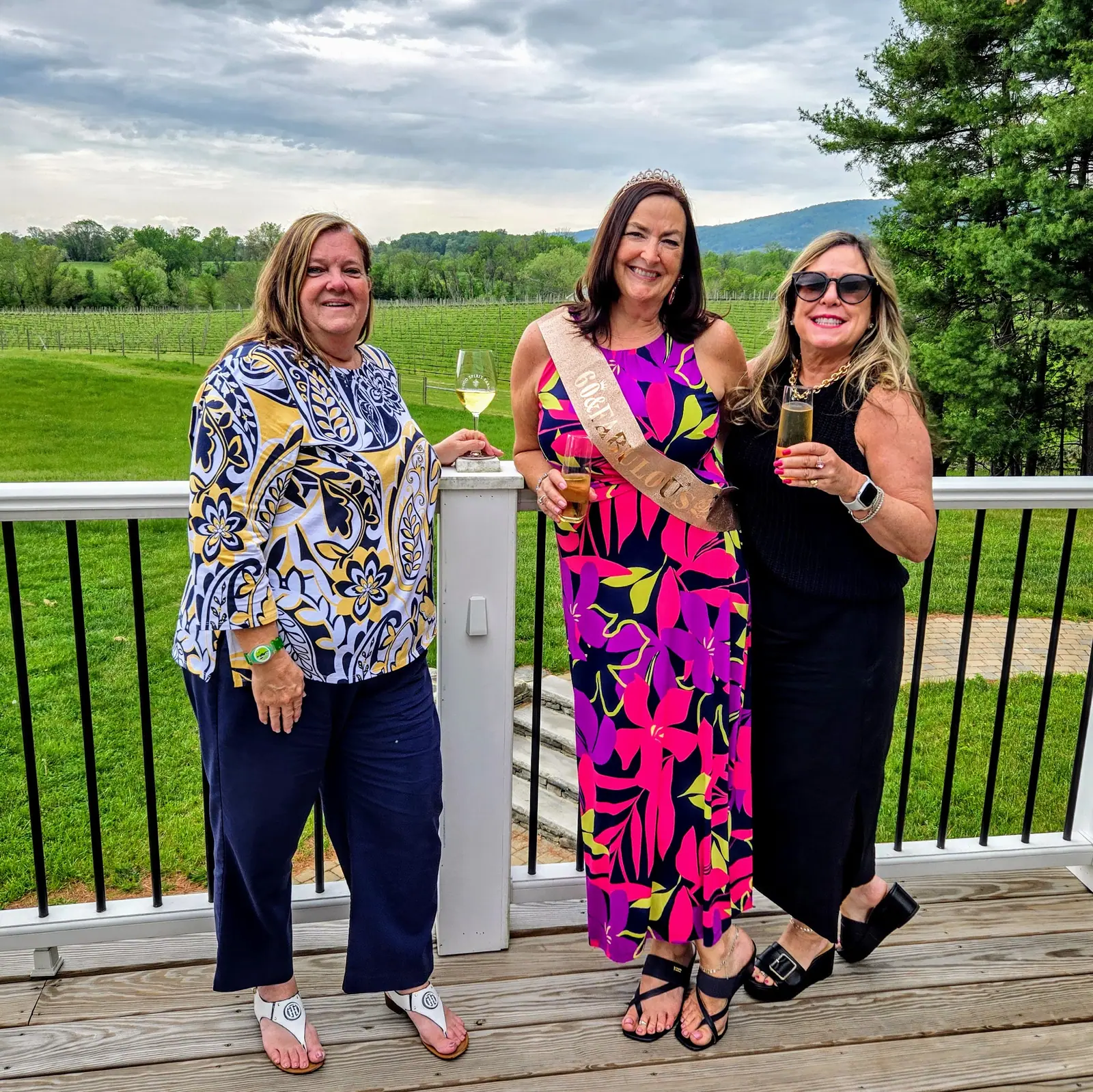 A bride-to-be wearing a sash with friends on a winery deck