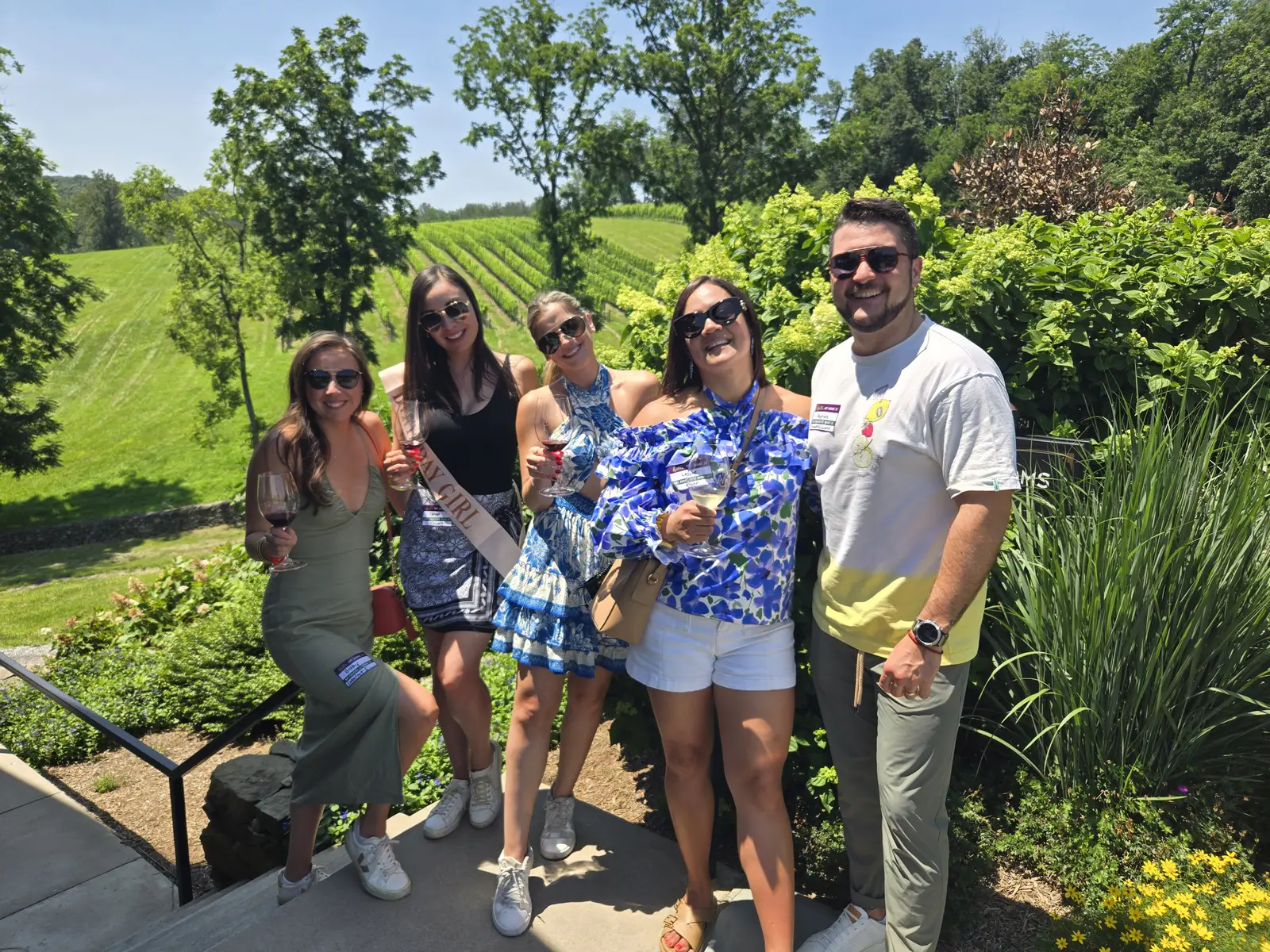 A group of guests with wine glasses on the steps outside a winery