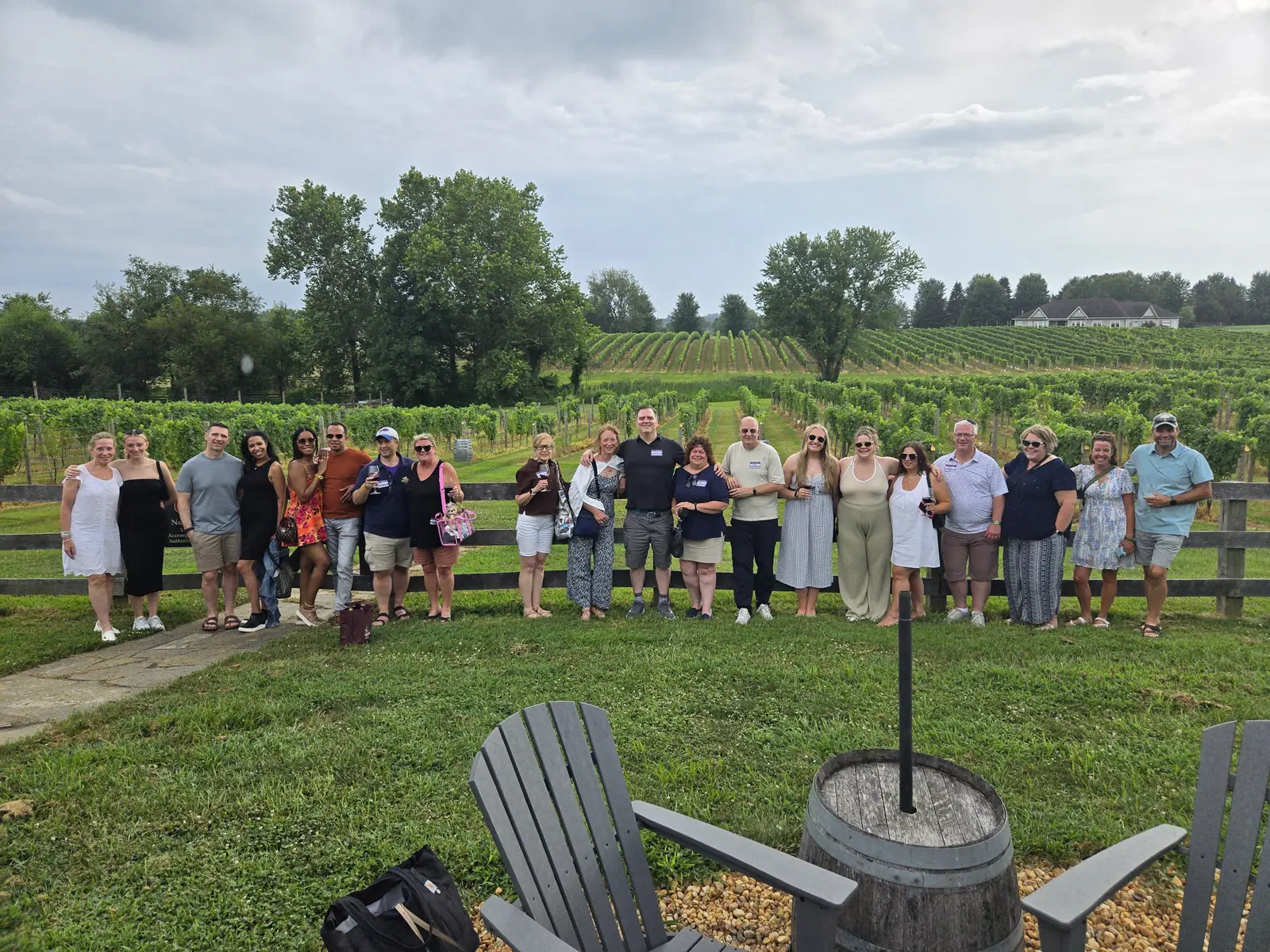 A large group photographed outdoors in front of the vineyard