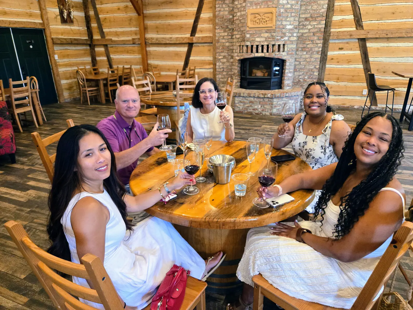 Guests at a round table in a timber-framed winery tasting barn