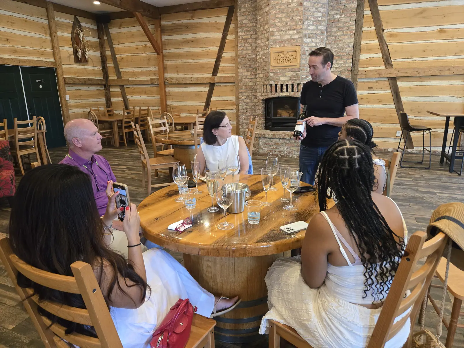 Guests seated at a round table for a tasting in a winery barn