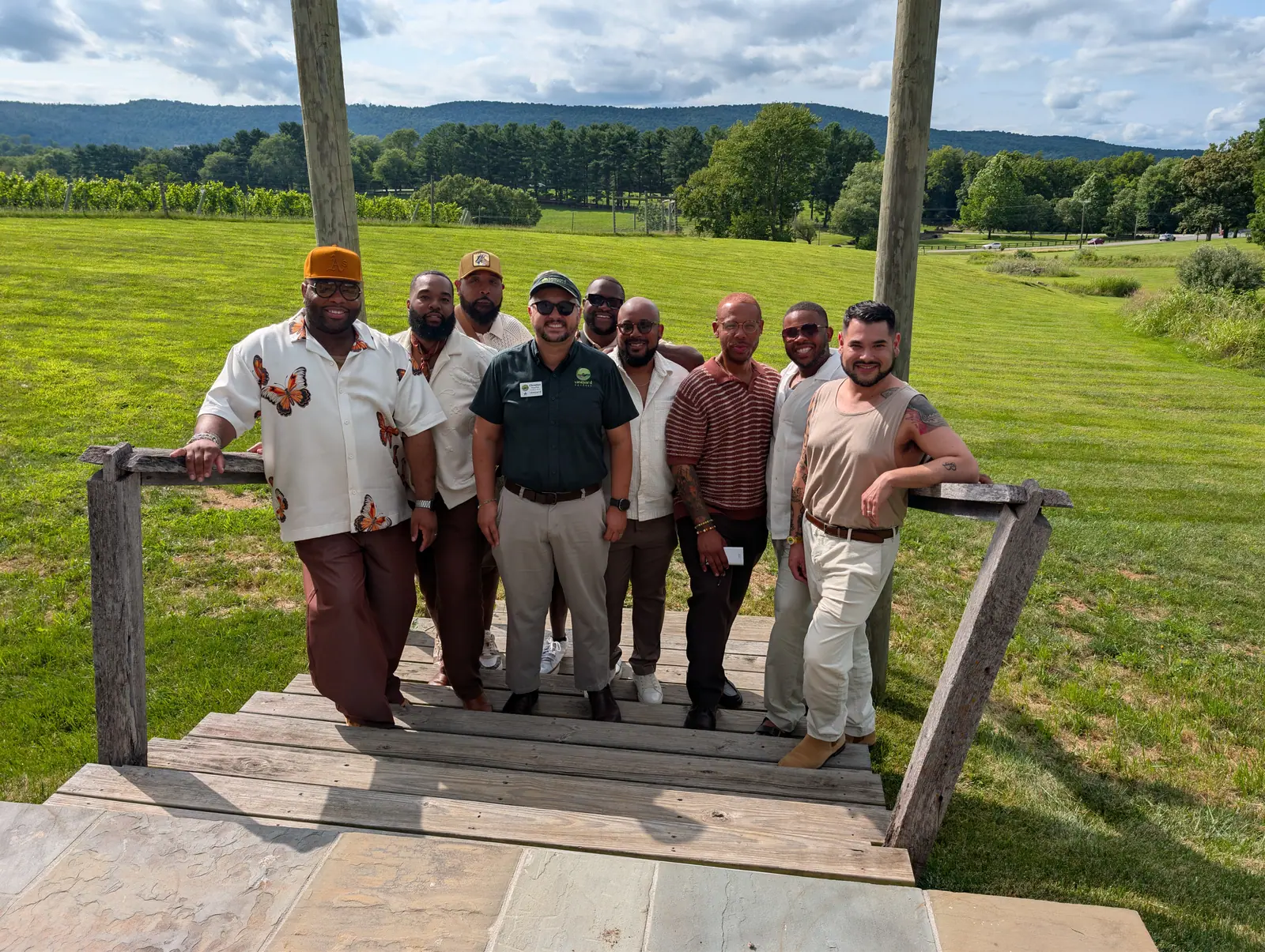 A company team gathered on a winery porch with the vineyard behind them