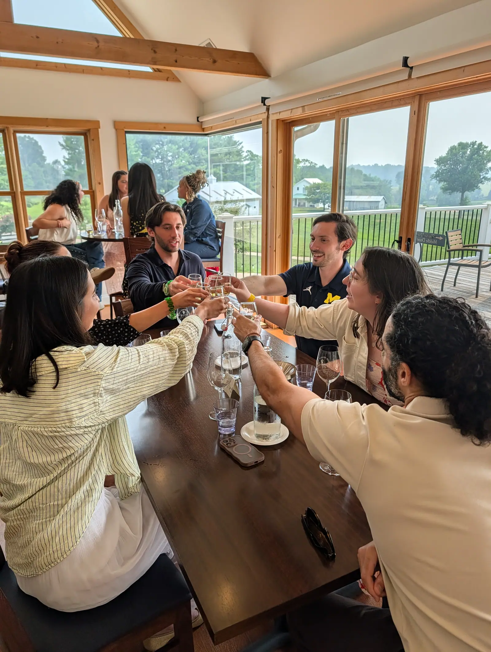 Guests raising their glasses together in a toast around a tasting table