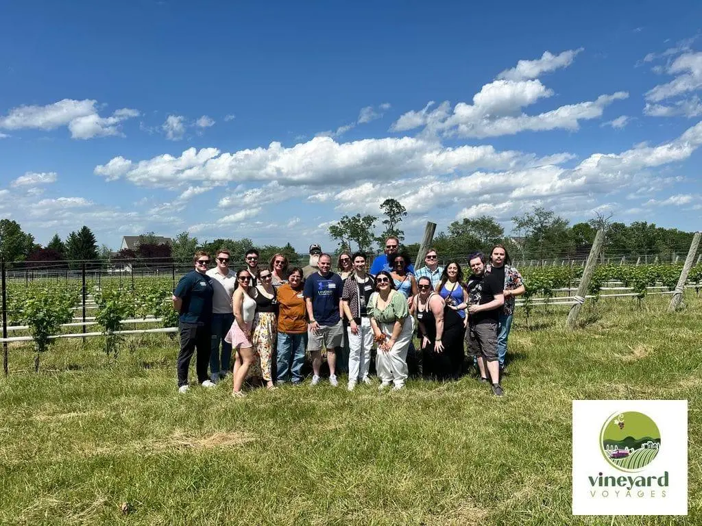 A large group gathered together among vineyard rows during a Vineyard Voyages winery outing