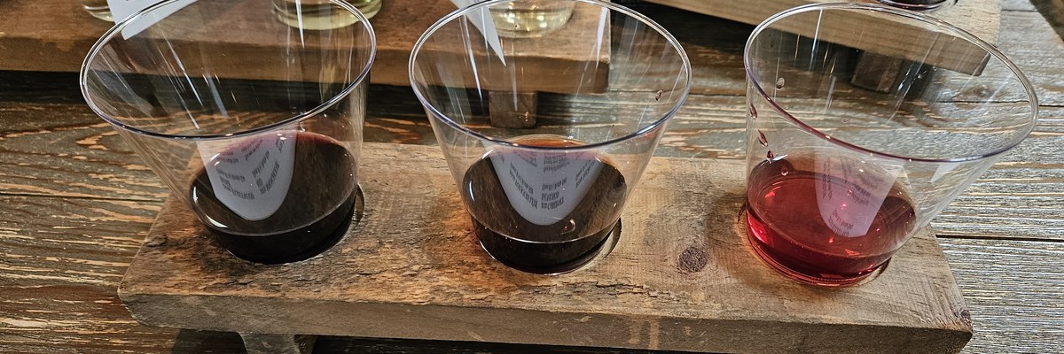 A flight of three wines on a wooden tasting table