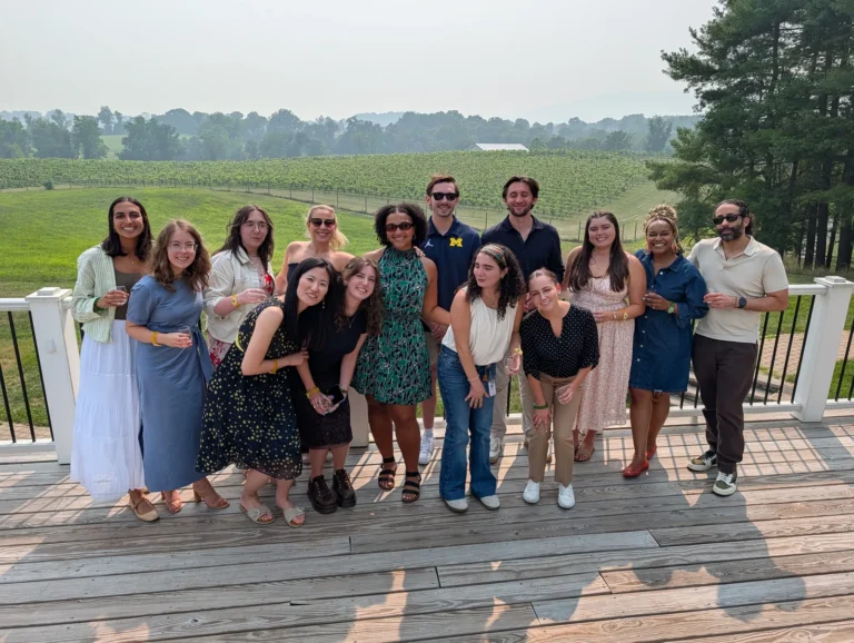 A group of guests on a winery deck overlooking the vineyard