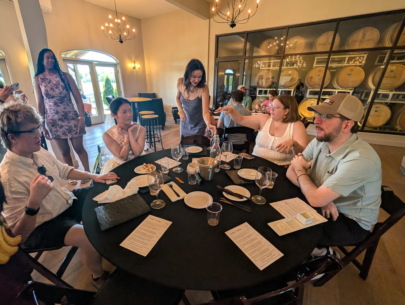 Guests raising glasses around a round table inside a winery tasting room