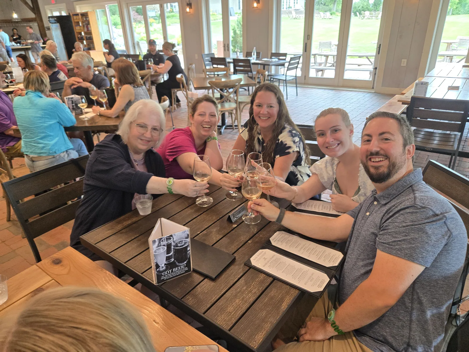 Guests toasting with wine glasses at a table in a winery tasting room
